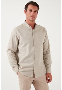 Camicia beige a maniche lunghe con colletto button-down, realizzata in tessuto testurizzato, con una placca frontale con bottoni e una vestibilità comoda.