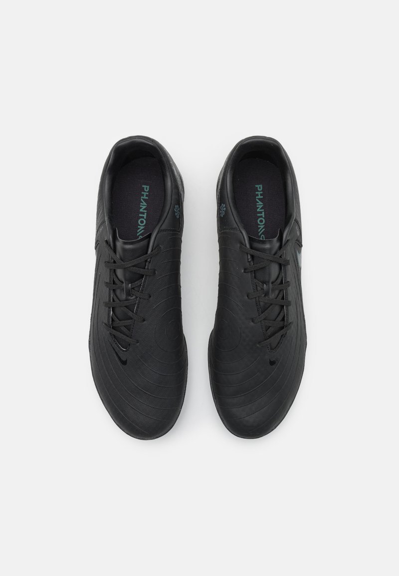 Zapatillas deportivas negras con un diseño circular texturizado, que presentan un cierre con cordones en la parte delantera y un interior acolchado. La marca es visible en las plantillas.