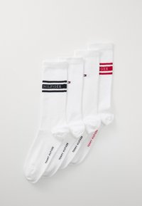 Vier Paar weiße Baumwollsocken mit gerippter Textur. Jedes Paar hat ein individuelles Logo: zwei in Schwarz, eines in Blau und eines in Rot.