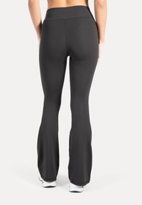 Svarta träningsbyxor med utsvängda ben och hög midja, gjorda av slät, stretchig tyg. Har en åtsittande passform och utsvängda benslut.
