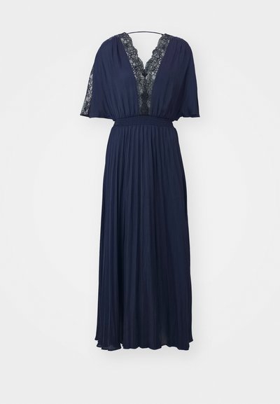 Tumši zila maksi kleita ar irtzako svārkiem, dziļu V-veida kakla izgriezumu, melnu mežģīņu apdari uz kakla izgriezuma un piedurknēm, kā arī savāktu jostu pakarināta.