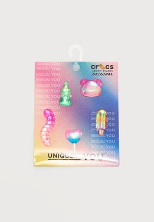 Πέντε πολύχρωμα, διαφανή γοητικά Crocs Jibbitz σε σχήμα μπιμπερό, κεφαλής αρκούδας, σκουληκιού, καρδιάς σε ξυλάκι και γρανίτας σε κάρτα με βαθμιδωτό ροζ-μπλε-κίτρινο χρώμα.