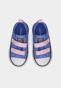Ζευγάρι μπλε παπούτσια Converse All Star για νήπια με ροζ ιμάντες Velcro και πολύχρωμες βούλες, φαίνονται από πάνω σε λευκό φόντο.