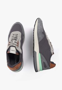 Adidași gri care combină materiale din piele întoarsă și plasă, având accente contrastante de culoare maro și o talpă texturată cu accente de verde mente.