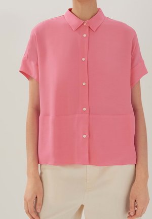 Blouse rose à manches courtes en tissu léger avec fermeture boutonnée à l'avant, dotée d'un col classique et d'une coupe décontractée.
