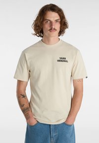 Béžové bavlněné tričko s krátkými rukávy a kulatým výstřihem, na levé části hrudi s černým potiskem "VANS ORIGINAL". Volný střih.