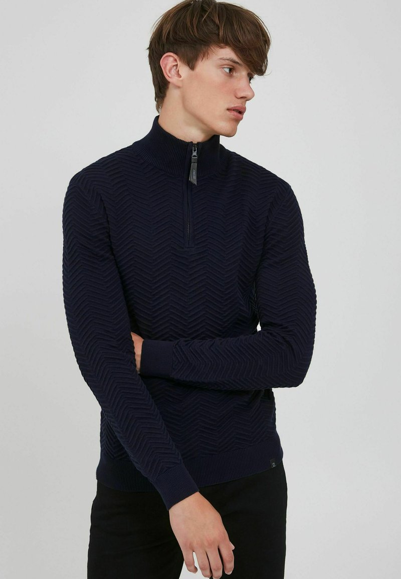 Maglione con colletto zip di colore blu navy con un motivo a zigzag testurizzato, caratterizzato da maniche lunghe e polsini e orlo a costine. Tessuto a maglia comodo.