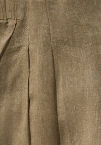 Κοντινό πλάνο καφέ υφάσματος με ορατή ραφή και λεπτομέρεια ραφής ρυμούλκησης.