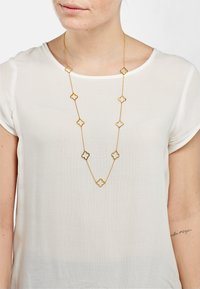 Gouden ketting met afwisselende bloemvormige schakel en ronde accenten. Lichtgewicht kettingontwerp gecombineerd met een lichtgekleurde top.