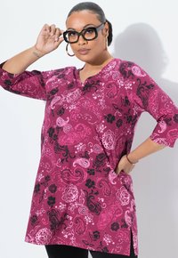 Magenta tuniek met zwarte en roze bloemen paisley patronen, ¾ mouwen, V-hals en zijsplitten, gemaakt van een zachte, rekbare stof.