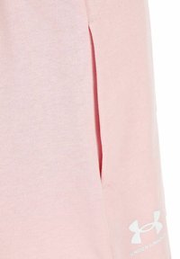 Pantalones cortos deportivos de color rosa claro, hechos de una tela suave, con una abertura lateral y un logo blanco de Under Armour en la parte inferior frontal.