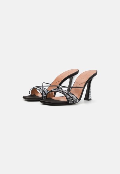 Black high-heeled sandals with a smooth black upper and a sparkling rhinestone-embellished heel, featuring crisscross straps.