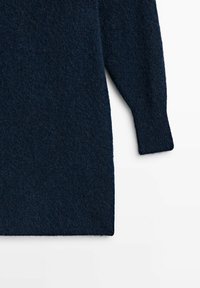 Pull bleu marine en texture floue, avec des manches longues et une coupe décontractée. L'ourlet se termine juste au-dessus de la taille.