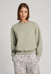 Lichtgroene sweatshirt met een ronde hals en verlaagde schouders, met een subtiele logo op de borst, gecombineerd met een geprint broek.