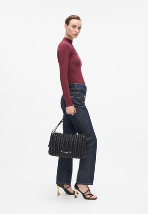 Sac à main noir matelassé avec un motif texturé, porté avec un jean foncé taille haute et un haut bourgogne à manches longues, associé à des chaussures à lanières.