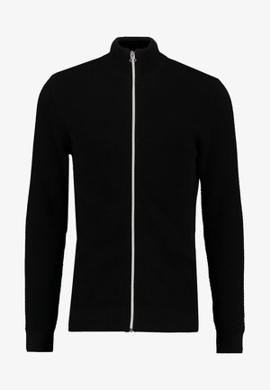 Schwarzer Zip-Up-Pullover mit hohem Kragen, strukturiertem Strickmuster und gerippten Bündchen sowie Saum. Verfügt über einen kontrastierenden weißen Reißverschluss.