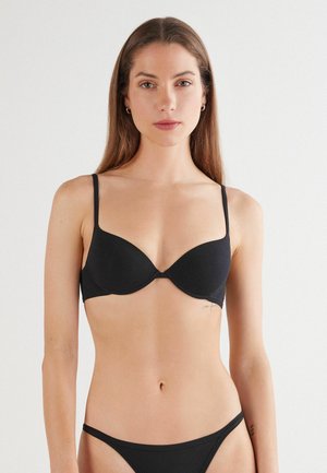 Zwarte plunge bh met dunne verstelbare bandjes, gladde textuur en uitneembare padding. Ontworpen voor een naadloze silhouet onder kleding.