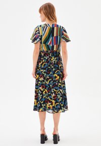 Robe maxi avec un haut rayé coloré et une jupe à motifs floraux. Confectionnée en tissu léger, avec des manches courtes évasées et une taille cintrée.