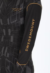 Maglietta sportiva nera a maniche lunghe con un motivo geometrico grigio, accentuata da un logo dorato "SWEDEMOUNT" lungo il braccio sinistro.