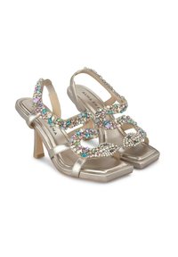 Sandali con tacco alto in oro metallizzato, decorati con intricate gemme di diversi colori, con punta quadrata e cinturini alla caviglia.