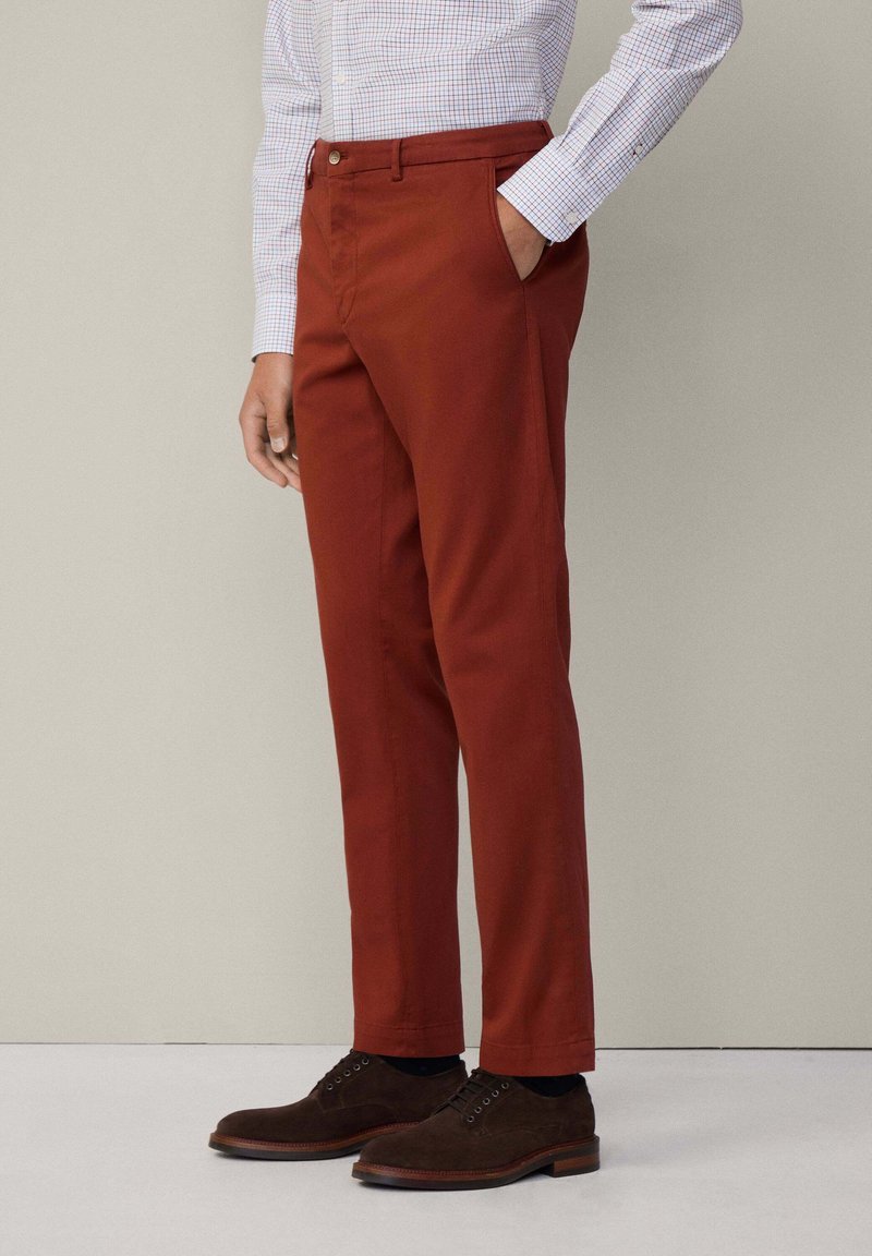 Slim-fit, verbrande oranje chinos van katoen, met zijzakken en een gladde textuur. Gecombineerd met donkerbruine suède schoenen.