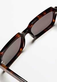 Zonnebril met schildpadprint, glanzende afwerking, rechthoekige vorm en donker getinte glazen. Opvallend door de dikke monturen en het minimalistische ontwerp.