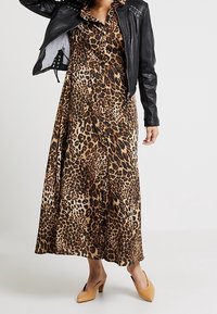 Maxi šaty s leopardím potiskem z měkké látky, s volánkovým výstřihem, doplněné o přiléhavý černý kožený křivák a béžové podpatky.