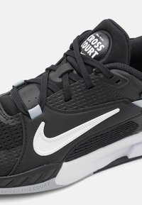 Čierne atletické tenisky s textúrovaným syntetickým zvrškom, biely znak Nike, čierne šnúrky a vypolstrovaný jazyk s brandingom "CROSS COURT".