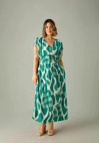 Robe maxi en vert et blanc avec un motif abstrait, fabriquée en tissu léger, présentant un décolleté en V, des bretelles réglables et une coupe décontractée.