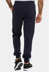 Marina joggers tillverkade av mjukt tyg med elastisk midja, avsmalnande mudd och sidofickor. Kombinerade med svarta träningsskor.