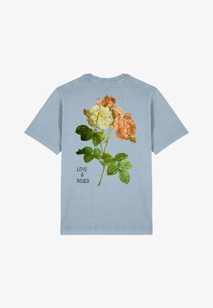 Zils kokvilnas T-krekls ar ziedu dizainu, kurā redzami rozā un dzelteni ziedi, zaļas lapas un uzraksts "MĪLESTĪBA UN ROŽAS" melnā krāsā.