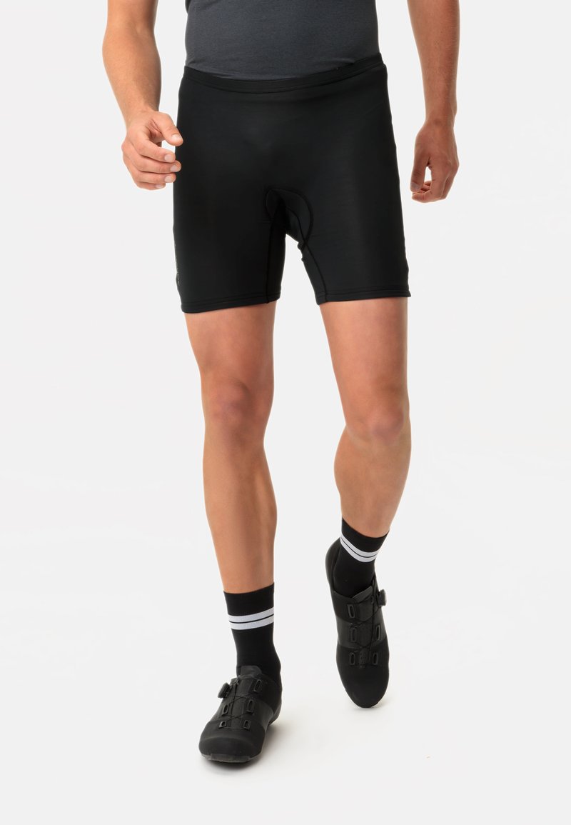 Shorts da ciclismo neri realizzati in tessuto elasticizzato, caratterizzati da una vestibilità aderente, cuciture piatte e un inserto imbottito per il comfort. Indossati con scarpe e calze da ciclismo.