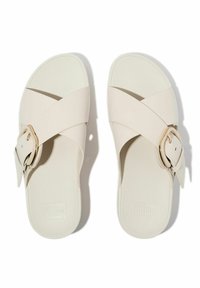 Sandalias deslizantes de imitación cuero blanco con correas cruzadas y un detalle de hebilla de tono dorado. Suela plana con plantilla texturizada y logo grabado.