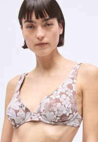 Brown floral print bikini top with wide straps and a triangular design, featuring white flower patterns and a subtle texture.