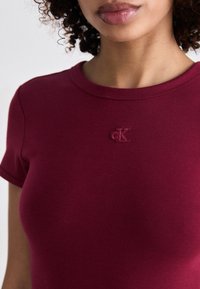 Bordo prilagođena majica s okruglim izrezom, sa zaštitnim "cK" logom na prsima, izrađena od mekanog, rastezljivog materijala.