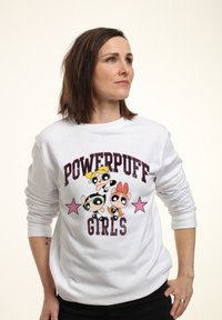 Maglione bianco con una grafica delle "Powerpuff Girls" che presenta personaggi dei cartoni animati colorati e accenti di stelle rosa. Design a maniche lunghe e colletto rotondo.