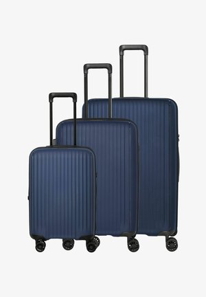 Three navy blue hard-shell suitcases of small, medium, and large sizes with extended black telescopic handles and four spinner wheels each.