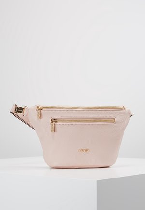Banane en cuir rose clair avec deux fermetures éclair dorées et une sangle réglable sur une surface blanche.