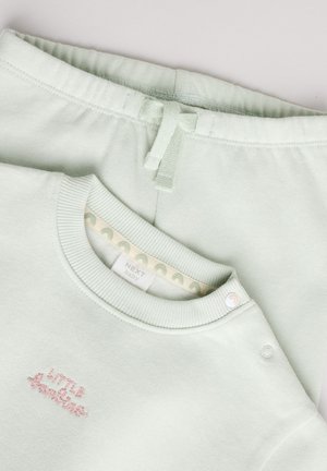 Svetlozelený detský komplet pozostáva z mikiny s výšivkou "Malý snílek" a zodpovedajúcich nohavíc s elastickým pásom a nastaviteľným šnúrkovaním.