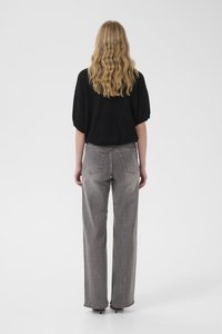 Volné černé tričko s krátkými rukávy ve spojení s vysokým pasem, rovnými šedými džínami s kapsami vzadu a jemným prošitím.