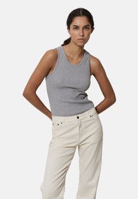Camiseta de algodón gris sin mangas con cuello redondo, combinada con pantalones de mezclilla color crema. La camiseta tiene un diseño ajustado y una textura suave.