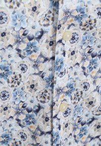 Bloemige knoopshirt met een lichtblauw en crèmekleurig patroon met ingewikkelde bloemen, zachte textuur en witte knopen aan de voorkant.