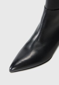 Black leather ankle boot with a pointed toe, sleek texture, and minimalist design. Smooth surface with no visible embellishments.