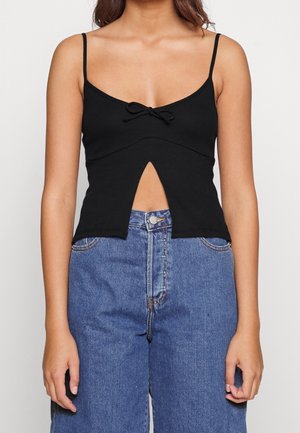 Czarny prążkowany krótki top na cienkich ramiączkach, z centralnie umieszczoną kokardą i trójkątnym wycięciem pod biustem. Materiał z mieszanki bawełny.