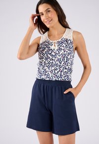 Mouwloze top met bloemenpatroon en kantdetail bij de halslijn, gecombineerd met marineblauwe elastische taille shorts. Licht en ademend materiaal.