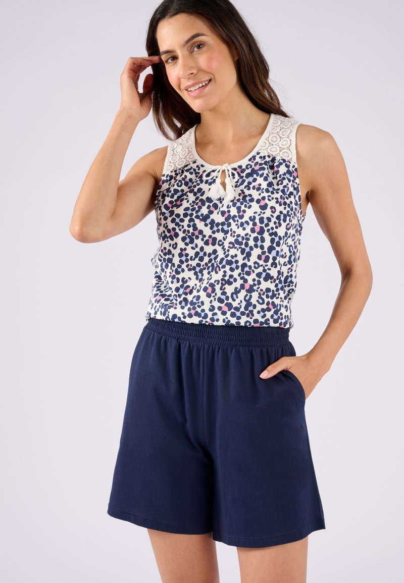 Mouwloze top met bloemenpatroon en kantdetail bij de halslijn, gecombineerd met marineblauwe elastische taille shorts. Licht en ademend materiaal.
