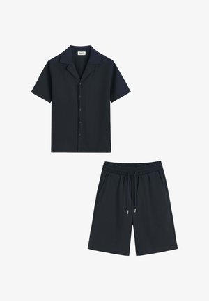 Chemise noire à manches courtes avec col et boutons, associée à un short noir à taille élastique avec cordon de serrage et poches latérales.