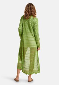 Langer, grüner, gestrickter Überwurf mit offenem Mesh-Design, langen Ärmeln und fließender Silhouette, der bis zur Mitte der Waden reicht.