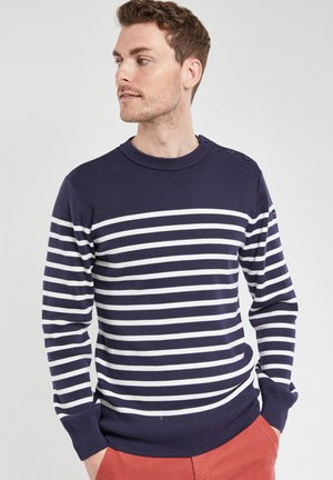 Navyblauw gestreepte trui met witte horizontale strepen, ronde halslijn, knopen detail op schouder, geribbelde mouwen en zoom.