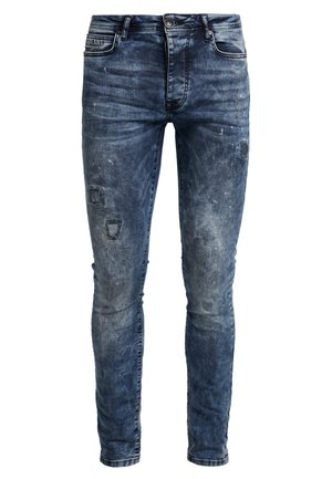 Jean skinny en bleu délavé avec des détails d'usure, doté d'une ceinture, de passants de ceinture et d'une texture de lavage subtile.